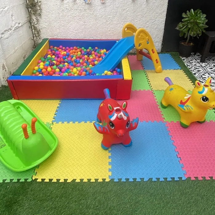 Montaje compacto en un patio pequeño: piscina de pelotas y resbalín sobre piso blando