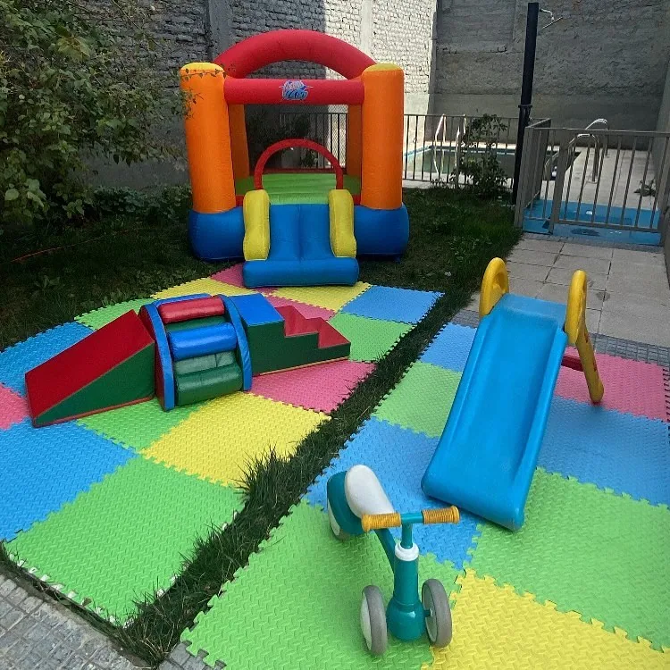 Inflable naranjo con módulos blandos y correpasillos en un patio con piscina al fondo