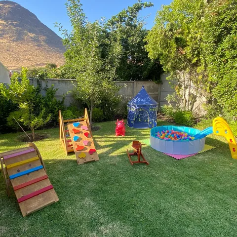 Arco Pikler, resbalín de madera y carpa con luz dorada de atardecer en un jardín amplio