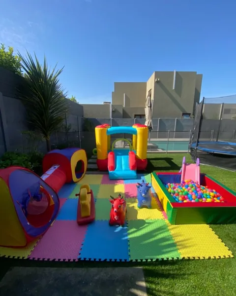 Plaza completa con carpa roja, túnel e inflable sobre pasto sintético