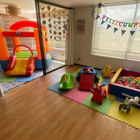 Living de departamento decorado para un cumpleaños con castillo inflable y banderín de feliz cumple